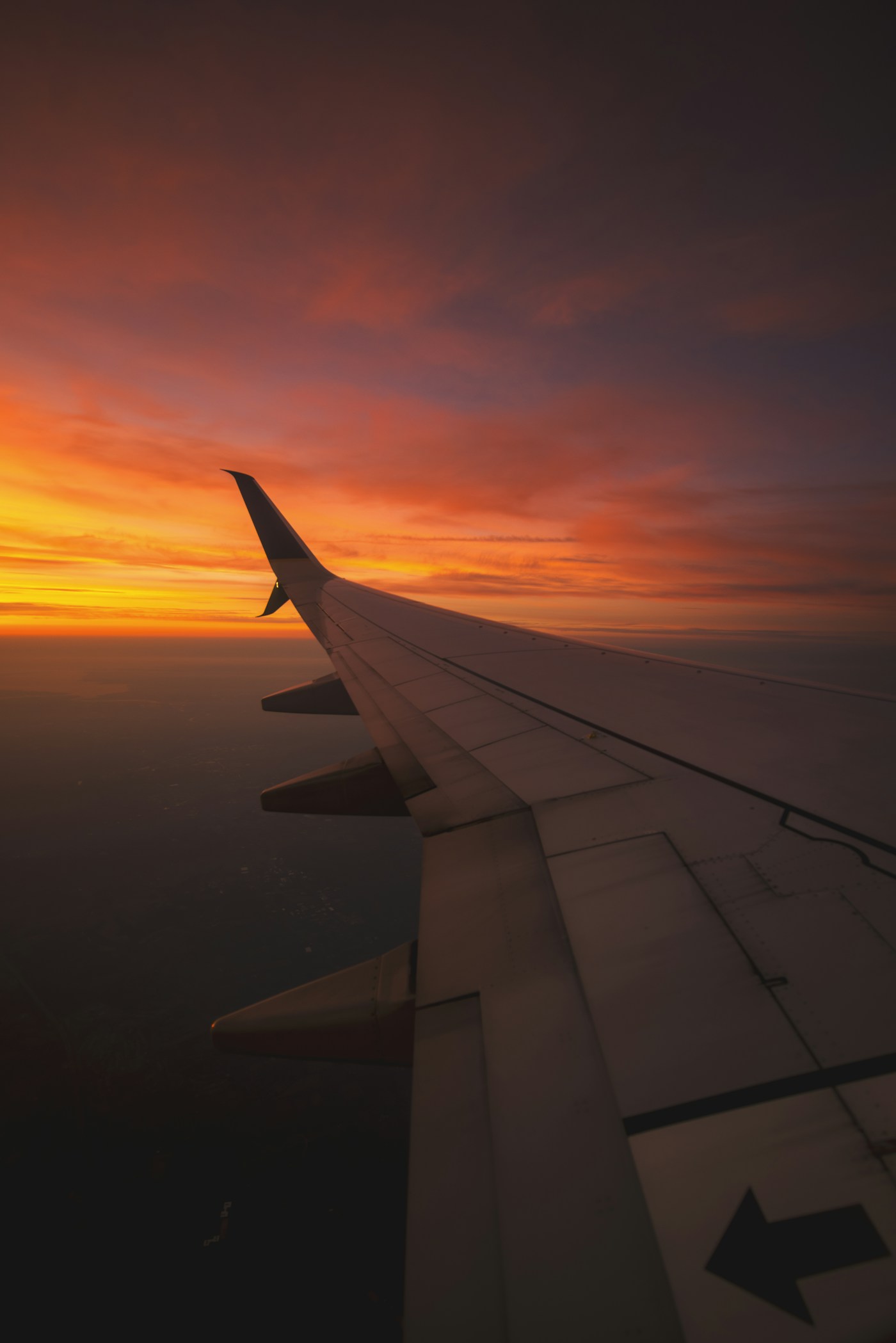 An airplane wing above clouds at sunset